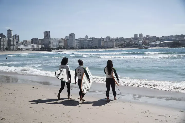 Varios surfistas entrando al mar en la playa del Orzán este miércoles / GUS DE LA PAZ