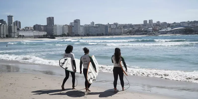 Varios surfistas entrando al mar en la playa del Orzán este miércoles / GUS DE LA PAZ